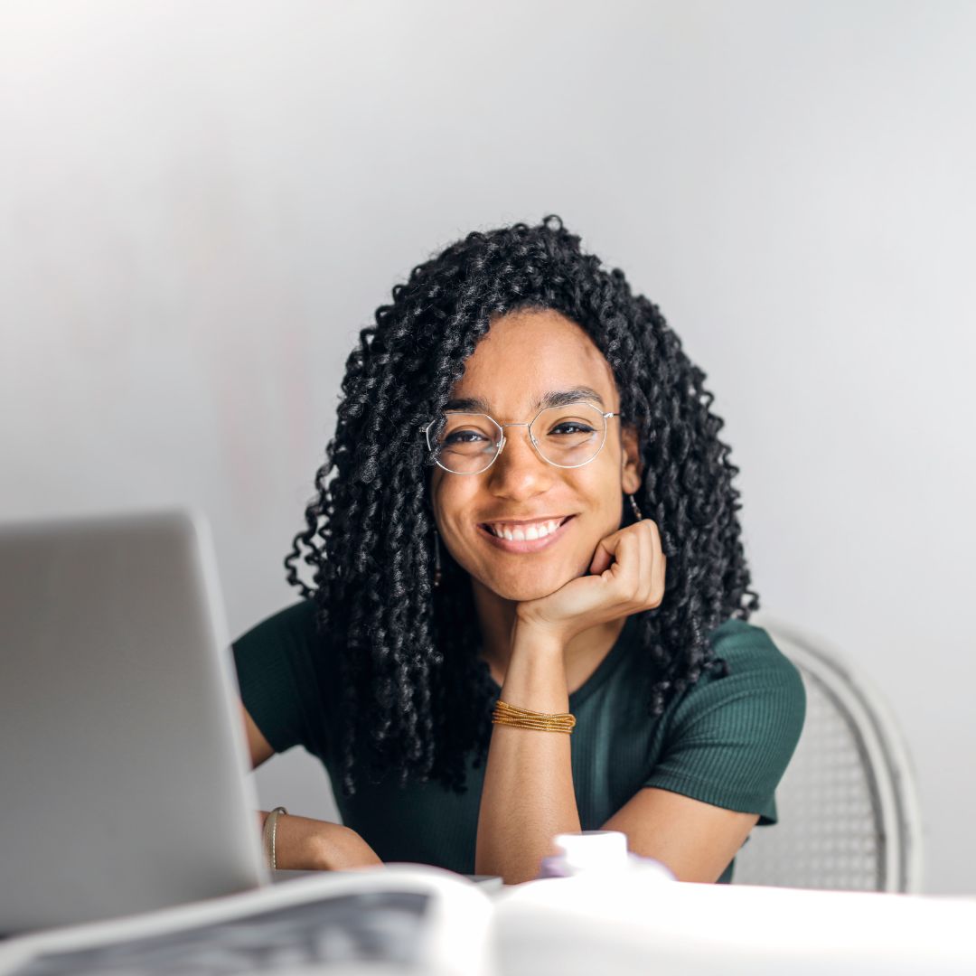 Happy ethnic woman sitting at table with laptop-Skilled Regional (provisional) visa (subclass 489) -widen migration expert